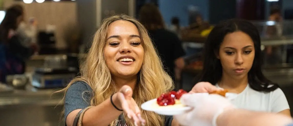 Student reaching for a plate for strawberries and waffles