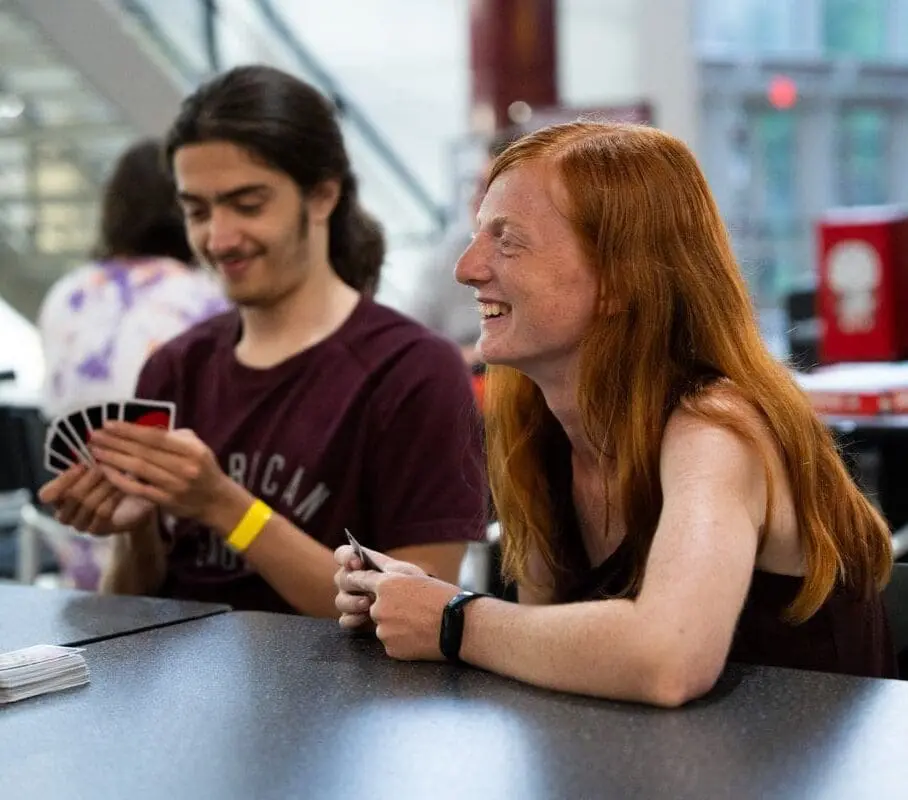 Students playing Uno card game at dining hall table